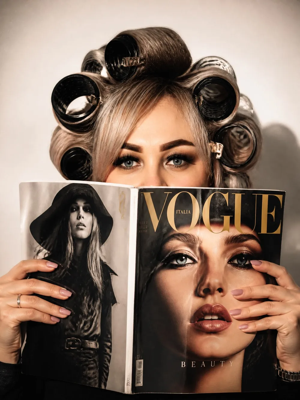 Девушка в бигуди закрывает лицо журналом Vogue