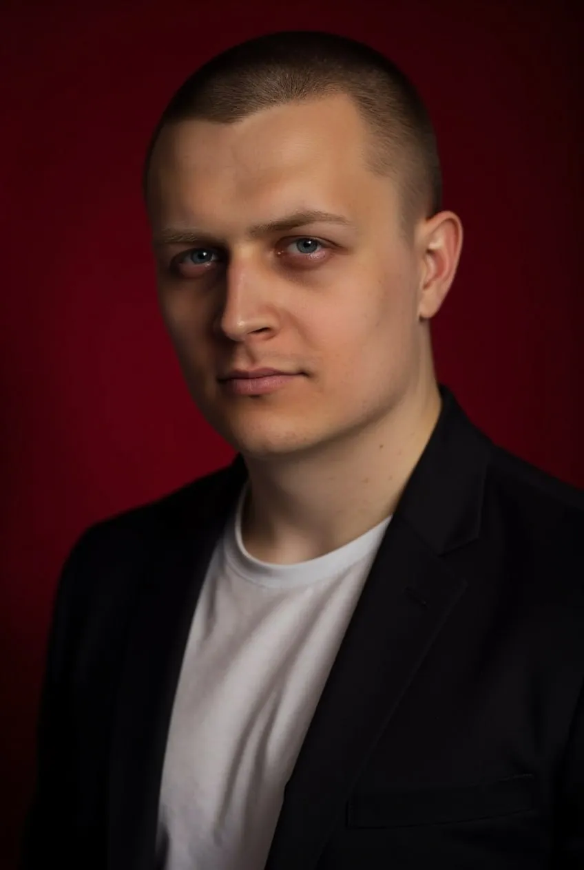 Мужчина в чёрном пиджаке на бордовом фоне